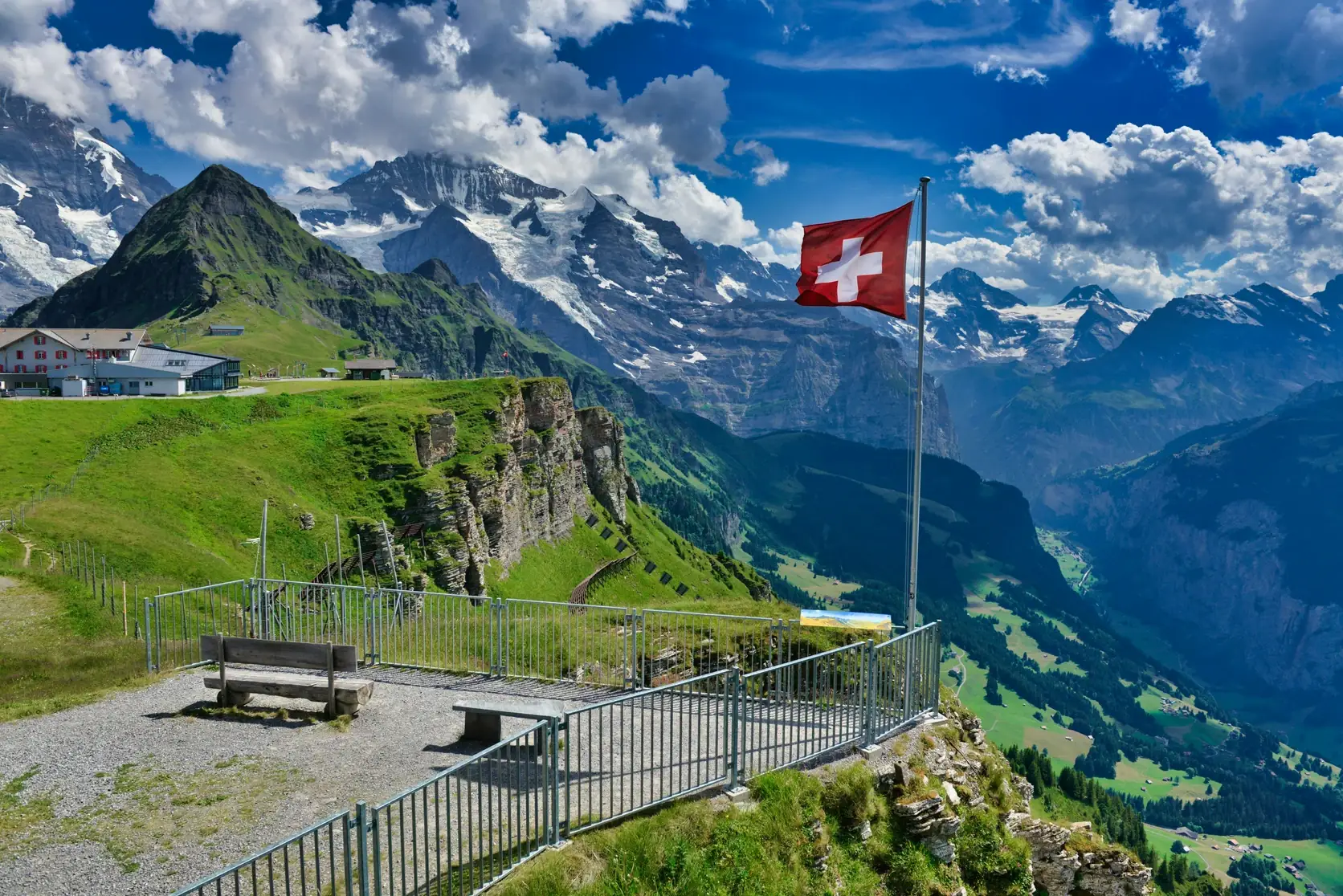 Le drapeau suisse à un belvédère du Männlichen, devant les sommets enneigés de l’Oberland bernois